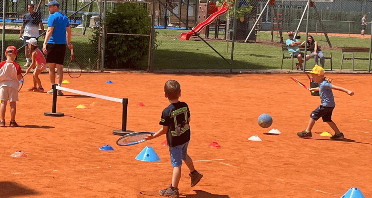 Familie spielt gemeinsam Tennis – Kinder lernen spielerisch und entwickeln Freude am Sport